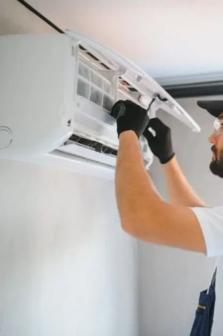 Technicien réalisant l’entretien d’une climatisation murale en nettoyant le filtre